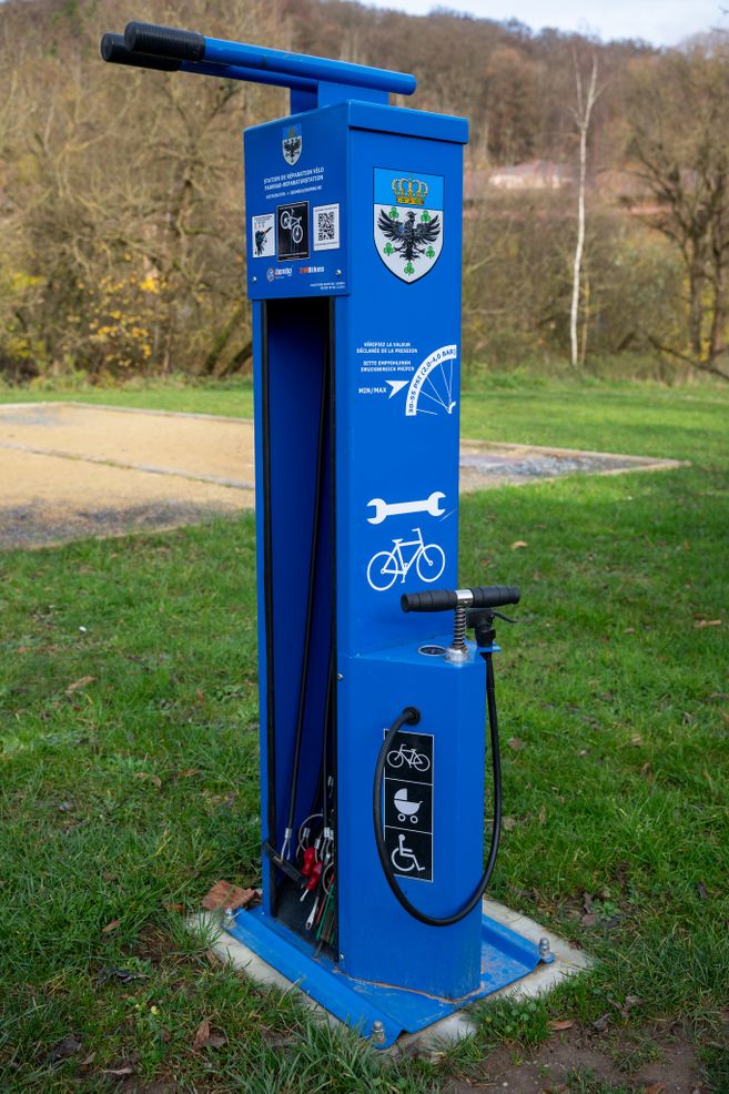 Eine blaue Fahrradreparaturstation im Freien mit Werkzeugen und einer Luftpumpe.