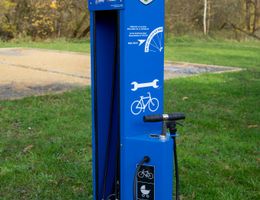 Eine blaue Fahrradreparaturstation im Freien mit Werkzeugen und einer Luftpumpe.
